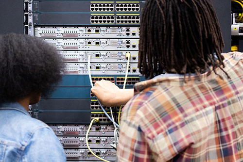 A man and a woman working on a server rack