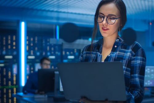 A woman working on a laptop in a server room