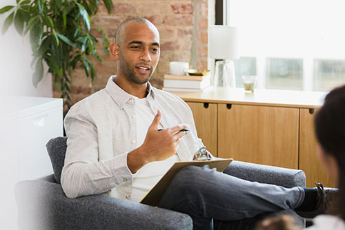 A man speaking while holding a clipboard